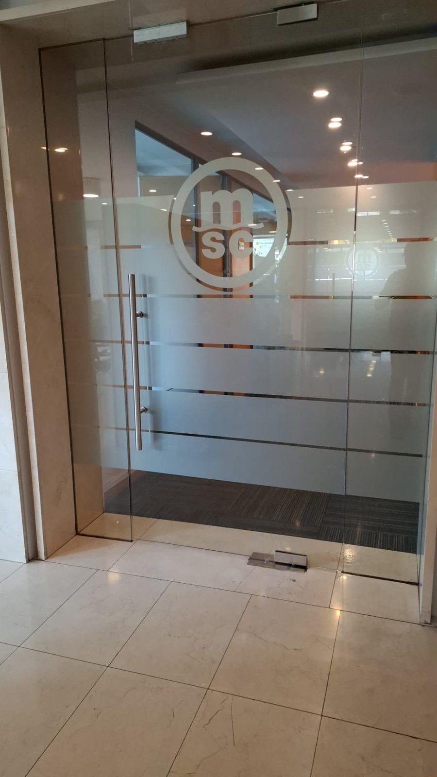 Empavonado con logo corporativo y franjas en puerta de vidrio