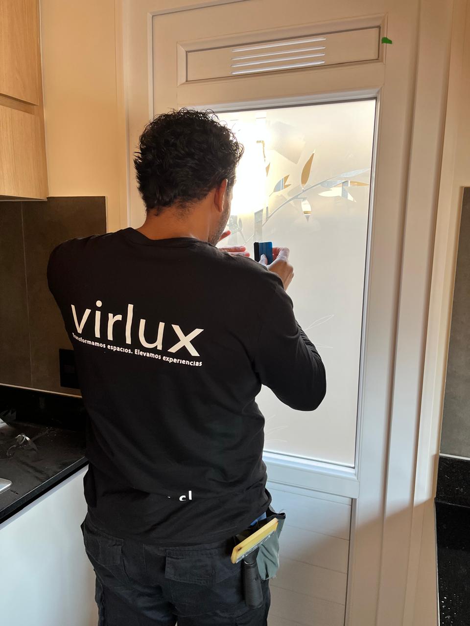 Instalador Virlux aplicando empavonado con diseño floral en puerta de vidrio